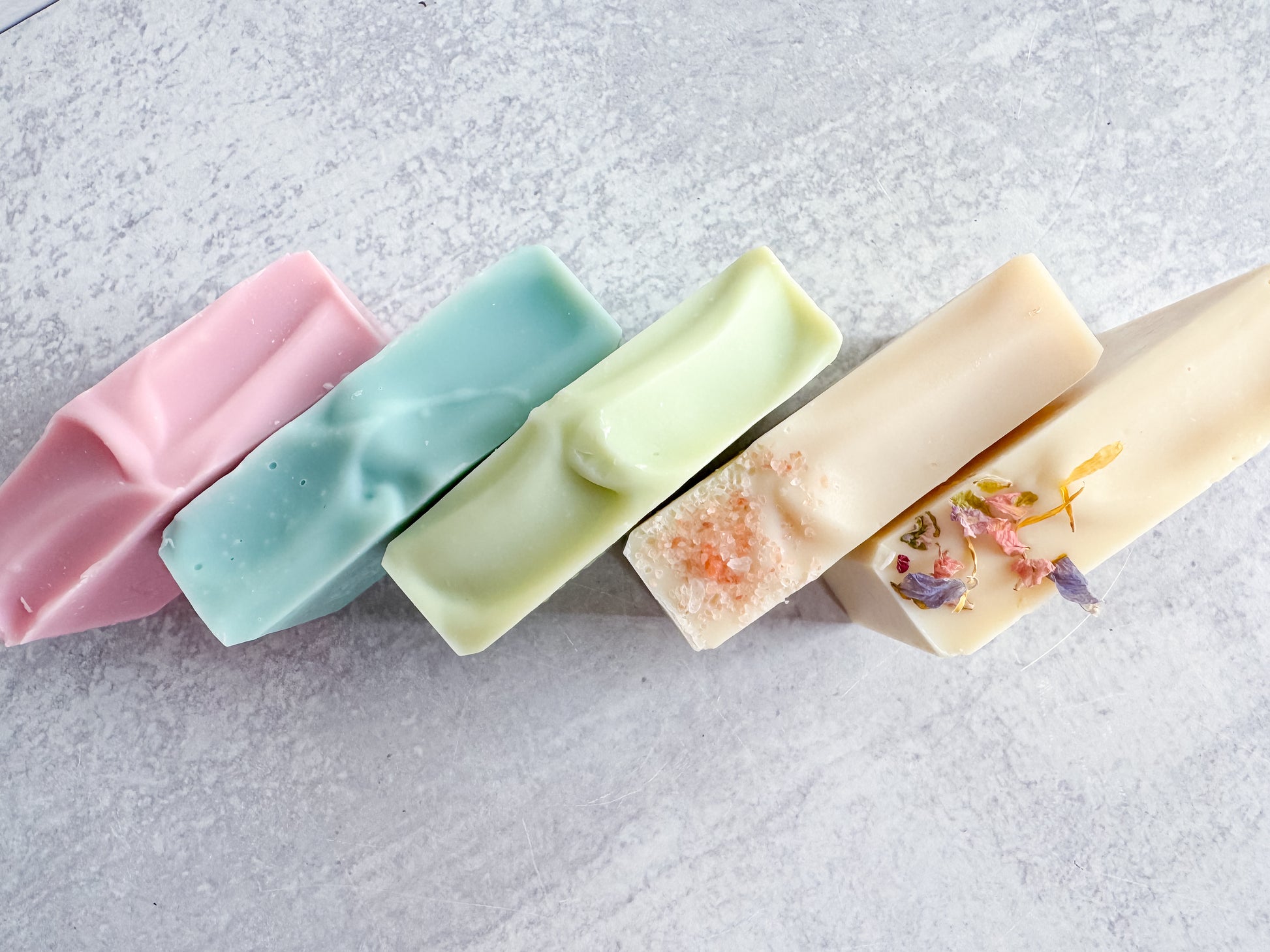 Five colorful soap bars on a textured surface