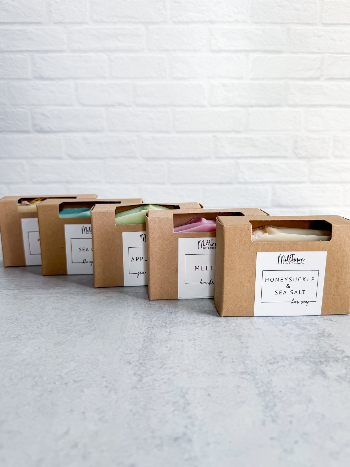 Row of soap bars in cardboard packaging with visible labels against a light brick wall Thomaston, GA
