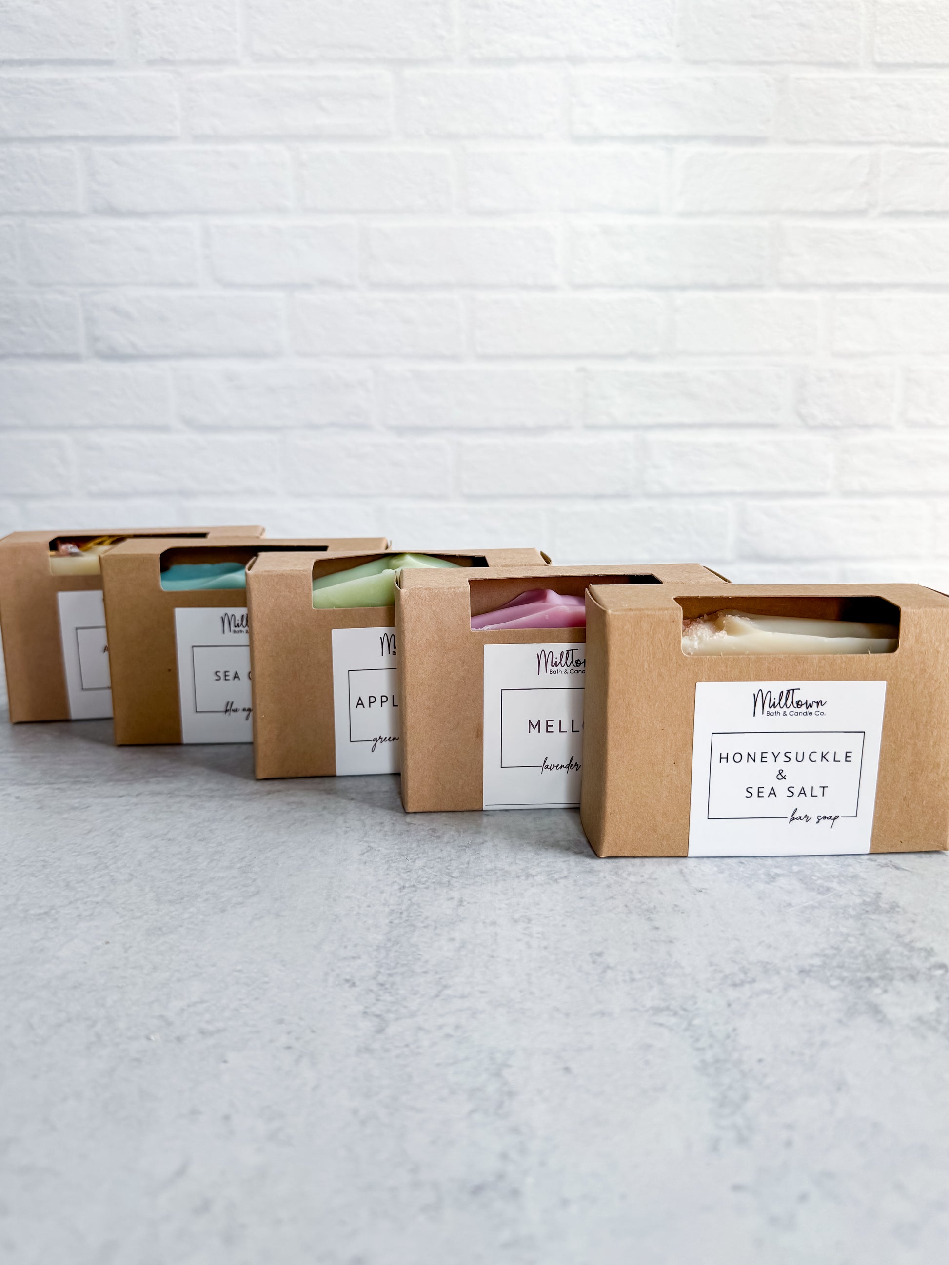 Row of soap bars in cardboard packaging with visible labels against a light brick wall Thomaston, GA
