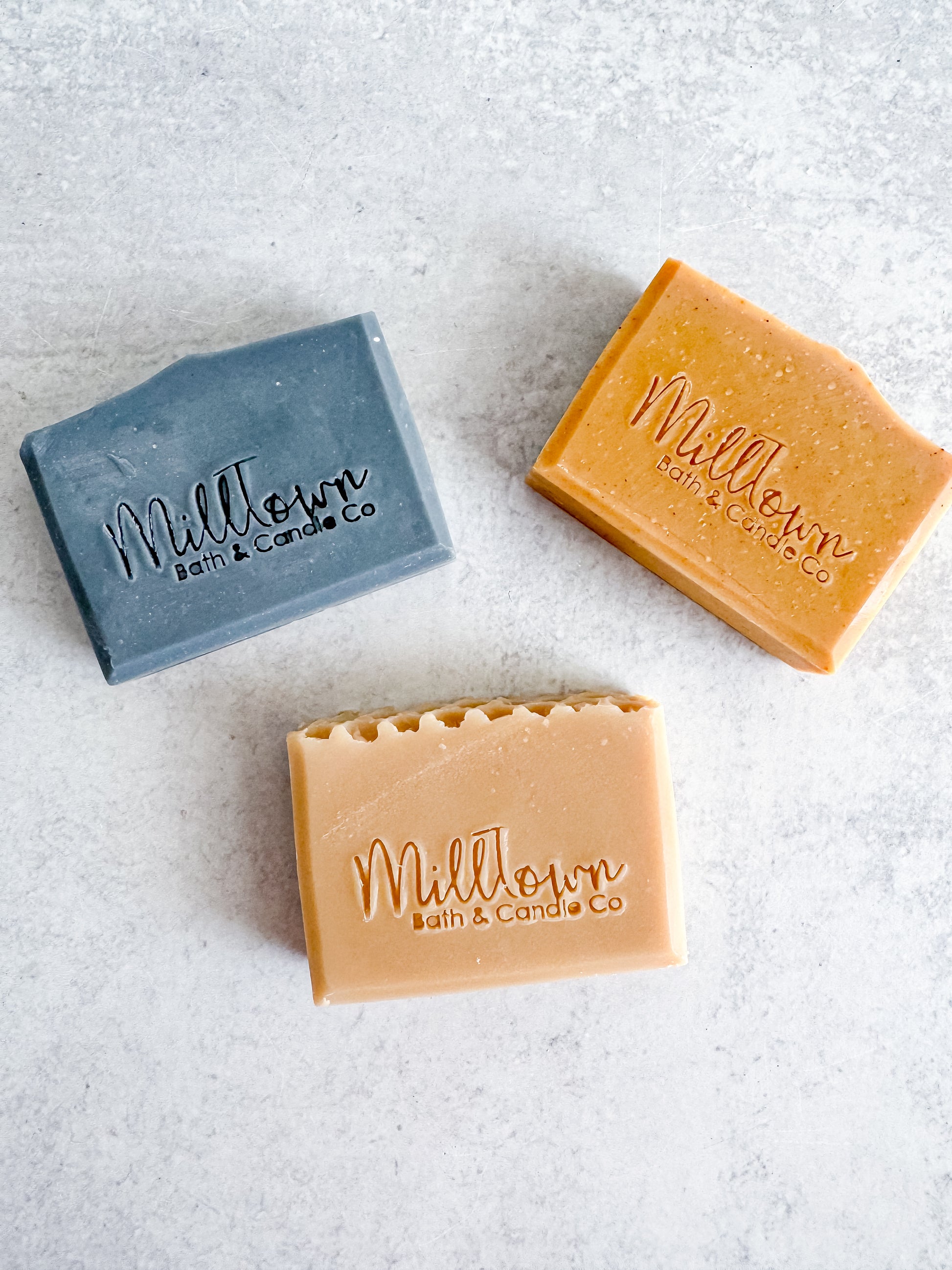 Three bars of soap from Milltown Bath & Candle Co on a textured surface