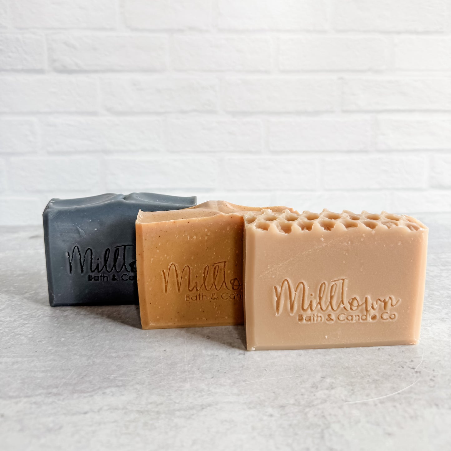Three bars of soap from MillTown Bath & Co on a textured white surface