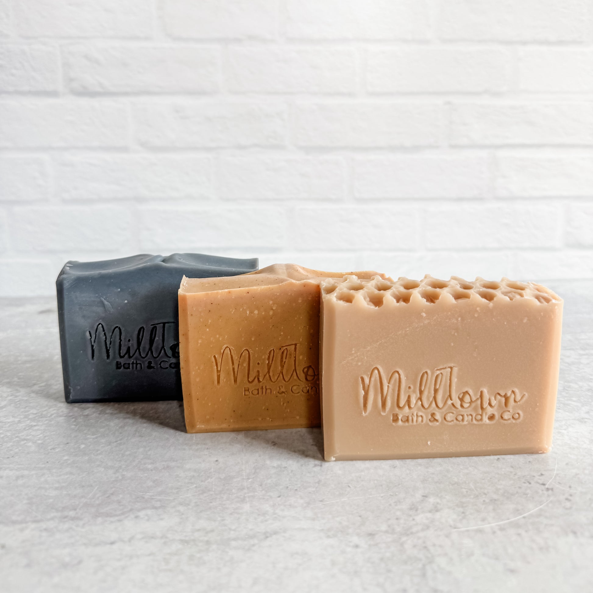 Three bars of soap from MillTown Bath & Co on a textured white surface