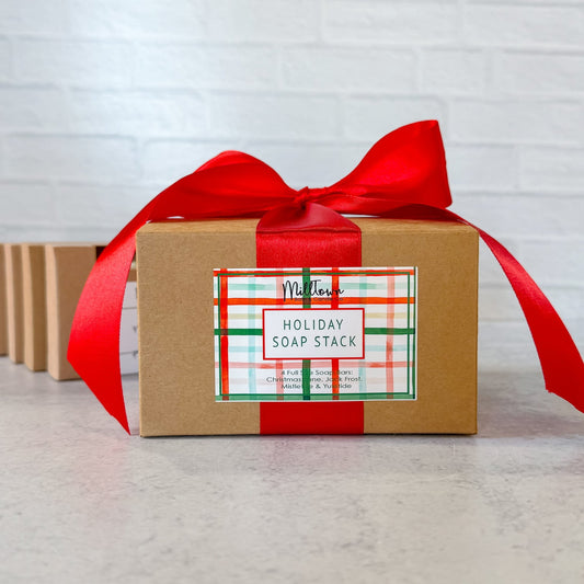 Gift box with a red ribbon labeled 'Holiday Soap Stack' on a light background