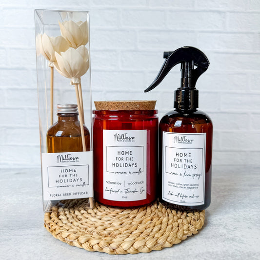 Set of home fragrance products including a candle, diffuser, and spray bottle on a woven mat with a white background. Gift set Christmas Thomaston, GA